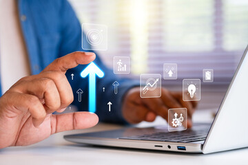 Business growth and digital success concept showing a man using laptop with glowing arrow and virtual icons representing data analytics, goal achievement, and innovation in technology