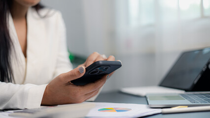 Businesswoman using smartphone for communication and financial work in modern office