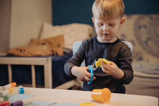 Little boy cutting play-doh developing fine motor skills