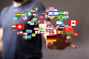 Conceptual image showing a hand connecting with flags representing countries around the world,...