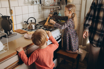 Children cooking pancakes together in home kitchen
