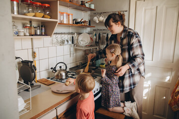 Mother preparing food with children in kitchen