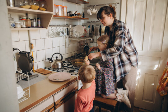 Mother teaching children cooking in home kitchen
