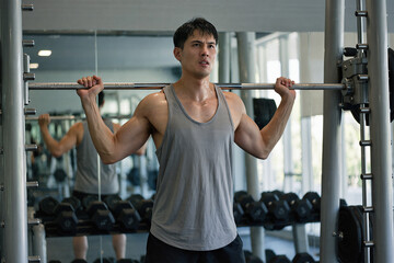 Determined man lifting weights in modern gym with sweat and focus, cinematic fitness scene