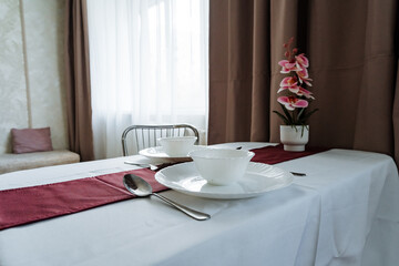 A beautifully elegant dining table setup featuring a pristine white tablecloth adorned with exquisite floral decorations, creating a perfect atmosphere for a delightful dining experience