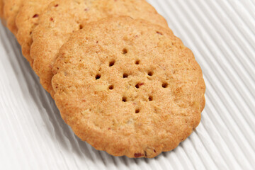 Round cookies with pieces of red cranberries on corrugated white packaging paper