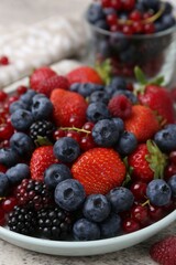 Different ripe berries on light grey textured table, closeup