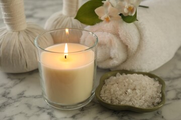 Beautiful spa composition with burning candle on white marble table, closeup