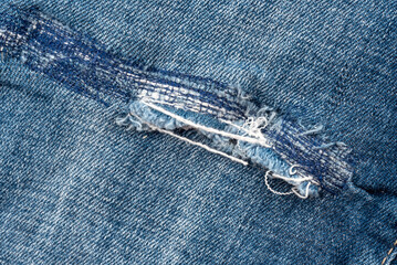 Hole in jeans close-up. Texture of faded denim