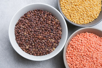 Assorted legumes displayed in three bowls, featuring brown, yellow, and red lentils, showcasing vibrant colors and textures, ideal for culinary and nutritional themes