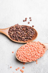 Brown and orange lentils displayed in wooden spoons on a textured surface, showcasing natural colors and organic shapes, perfect for culinary and health-related concepts
