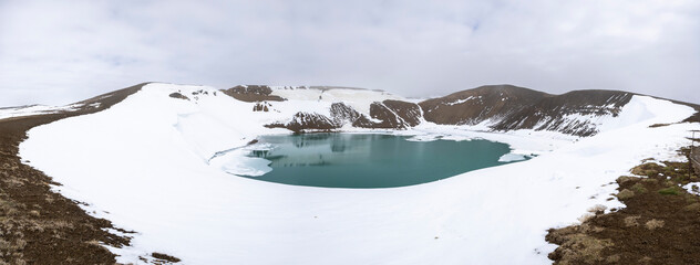 panorama of turquoise crater lake of Viti covered with snow, Krafla caldera, Lake M&yacute;vatn, North Iceland