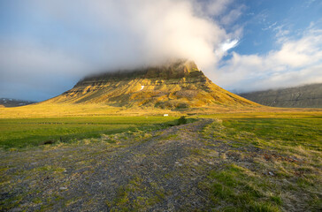 white clouds lit by evening lights sits on the top of the mountain near Kirkjufell , Snaefellsnes Peninsula, Iceland