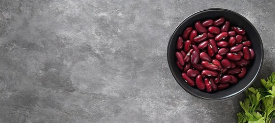 A bowl of red kidney beans placed on a textured grey stone background- showcasing natural color and simplicity.