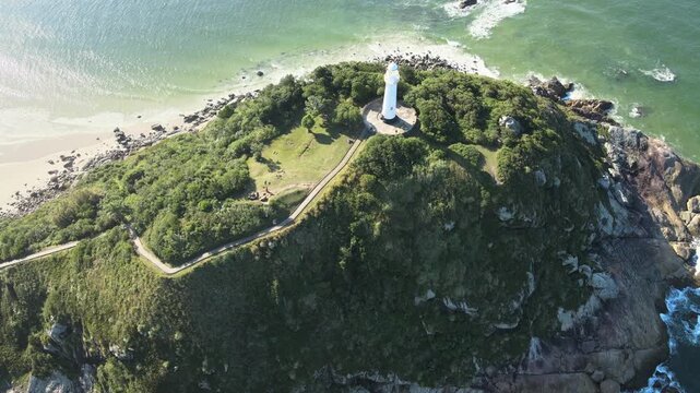Vista a&eacute;rea de drone do far&oacute;l das conchas da Ilha do Mel da praia de fora em Paranagu&aacute; no litoral paranaense com oc&ecirc;ano atl&acirc;ntico e c&eacute;u azul ao fundo no per&iacute;odo da tarde