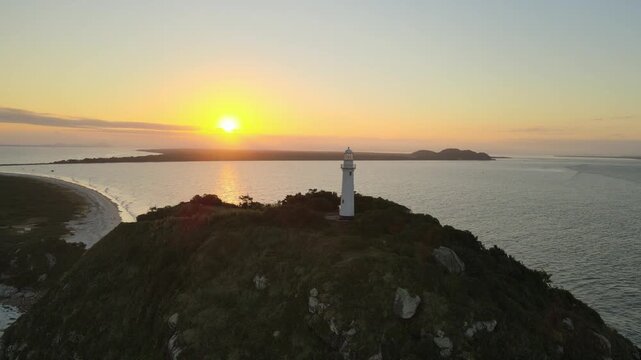 Vista a&eacute;rea com drone do far&oacute;l da conchas da Ilha do Mel em Paranagu&aacute; no litoral do Paran&aacute; com oceano atl&acirc;ntico ao p&ocirc;r-do-sol alaranjado