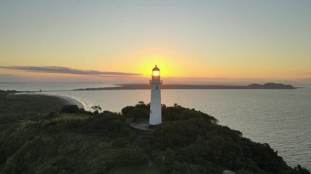 Vista a&eacute;rea com drone do far&oacute;l da conchas da Ilha do Mel em Paranagu&aacute; no litoral do Paran&aacute; com oceano atl&acirc;ntico ao p&ocirc;r-do-sol alaranjado