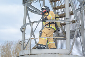 A firefighter in a helmet and protective clothing, with a breathing apparatus, climbs the stairs. In winter, firefighters conduct outdoor training. The rescue service.