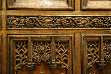 This close-up image shows the detailed bronze carvings on a cathedral door at St. Patrick's Cathedral in New York City. The ornate design includes floral motifs and grapevine patterns in Gothic style.