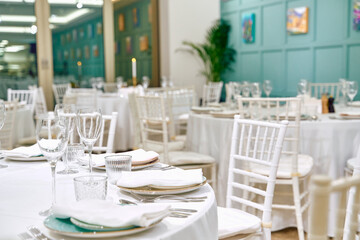Elegant Dining Setup Featuring White Tables, Fine Glassware, and Tastefully Decorated Walls in a Chic Restaurant Atmosphere Suitable for Special Occasions and Gatherings