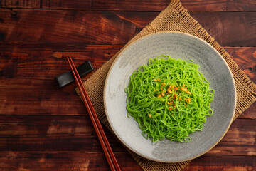 Cooked jade noodles or egg green noodle,topping with crispy garlic in a plate.(ba mee yok noodles).Top view.