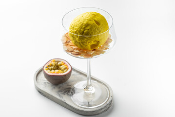 Creative food styling with lemon in wine glass filled with sliced almonds, passion fruit half on marble tray. Minimalist gourmet concept with vibrant tropical accents.
