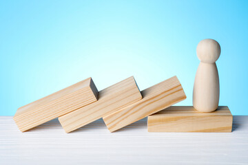 Risk. Fallen blocks and wooden figure on white table against light blue background