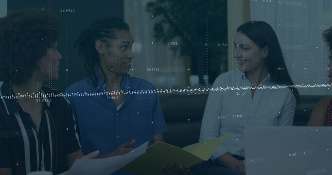 Colleagues reviewing colorful folders and papers in office lounge, with laptop and data overlay