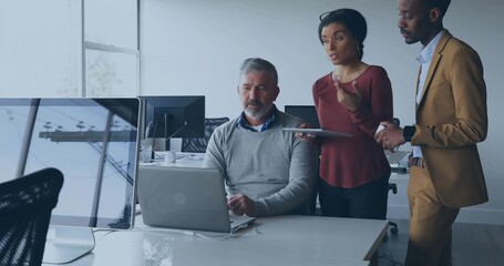 Working mature professional collaborating with colleagues in modern office, with laptop and tablet