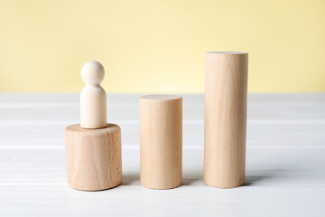 Wooden blocks and figure on white table against beige background, closeup