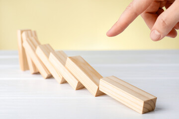 Risk. Woman pushing wooden blocks at white table against beige background, closeup