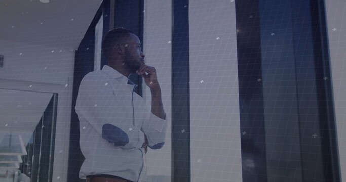 Gazing businessman wearing casual shirt leaning inside corridor, with glass panels and grid overlay