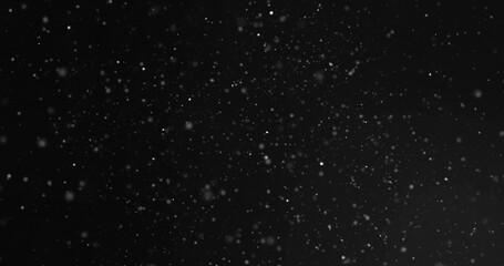 Drifting white snowflakes creating textured depth in nighttime outdoors, with glowing particles