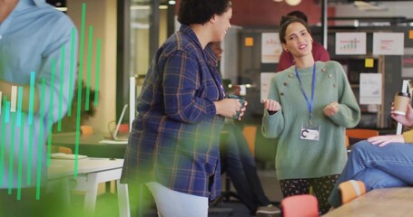 Gesturing woman in green knit sweater conversing in modern workspace, with ceramic mug, whiteboard