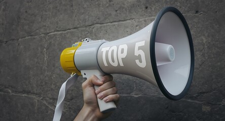 Hand holding white and yellow megaphone with top 5 text on concrete wall background