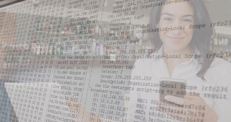 Working IT professional holding smartphone and typing on laptop at office desk, with code overlay