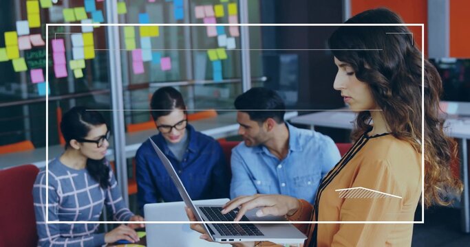 Standing woman holding laptop leading planning session in office, with sticky notes, copy space - Powered by Adobe