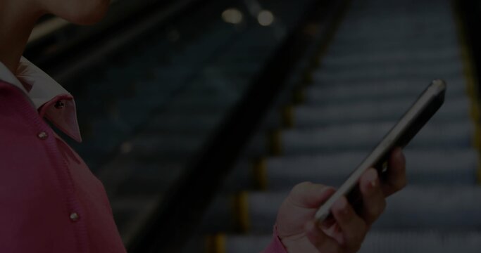 Holding smartphone and handrail in pink coat checking screen at station escalator steps, copy space