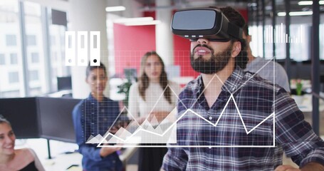 Testing VR simulation by casual man wearing headset at office desk, coworkers observing with tablet