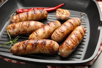 Pan with grilled sausages and spices on table, closeup
