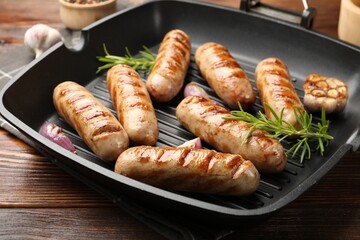 Pan with grilled sausages and spices on wooden table, closeup