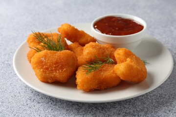Tasty chicken nuggets with sauce on light grey table, closeup
