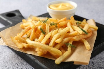 Tasty french fries with sauce on light grey table, closeup
