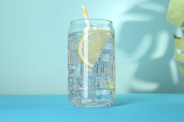 Refreshing water with lemon and ice on light blue background, closeup