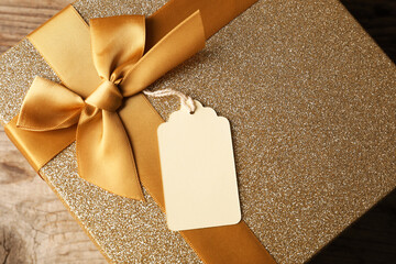 Blank tag and gift box on wooden table, top view