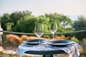 Obraz premium A Romantic Outdoor Dining Setup with Elegant Glassware and Plates Surrounded by Nature, Perfect for Special Occasions or Intimate Gatherings