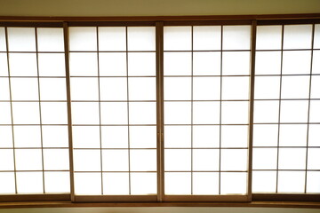 Traditional Japanese shoji sliding doors made of wooden frames and paper panels, minimal and serene interior design with natural light.