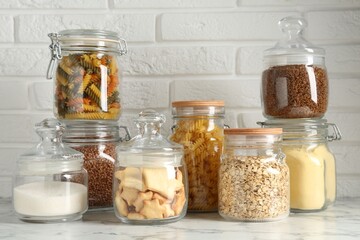 Glass jars with different products on white marble table