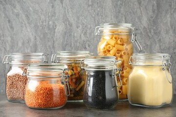 Glass jars with different products on grey table