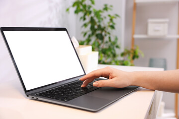 Woman working with laptop at white table indoors, closeup. Mockup for design